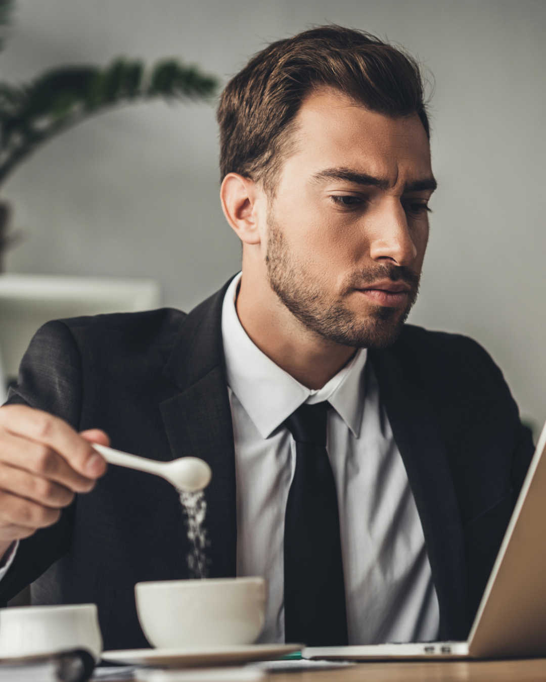 man adding sugar to coffee