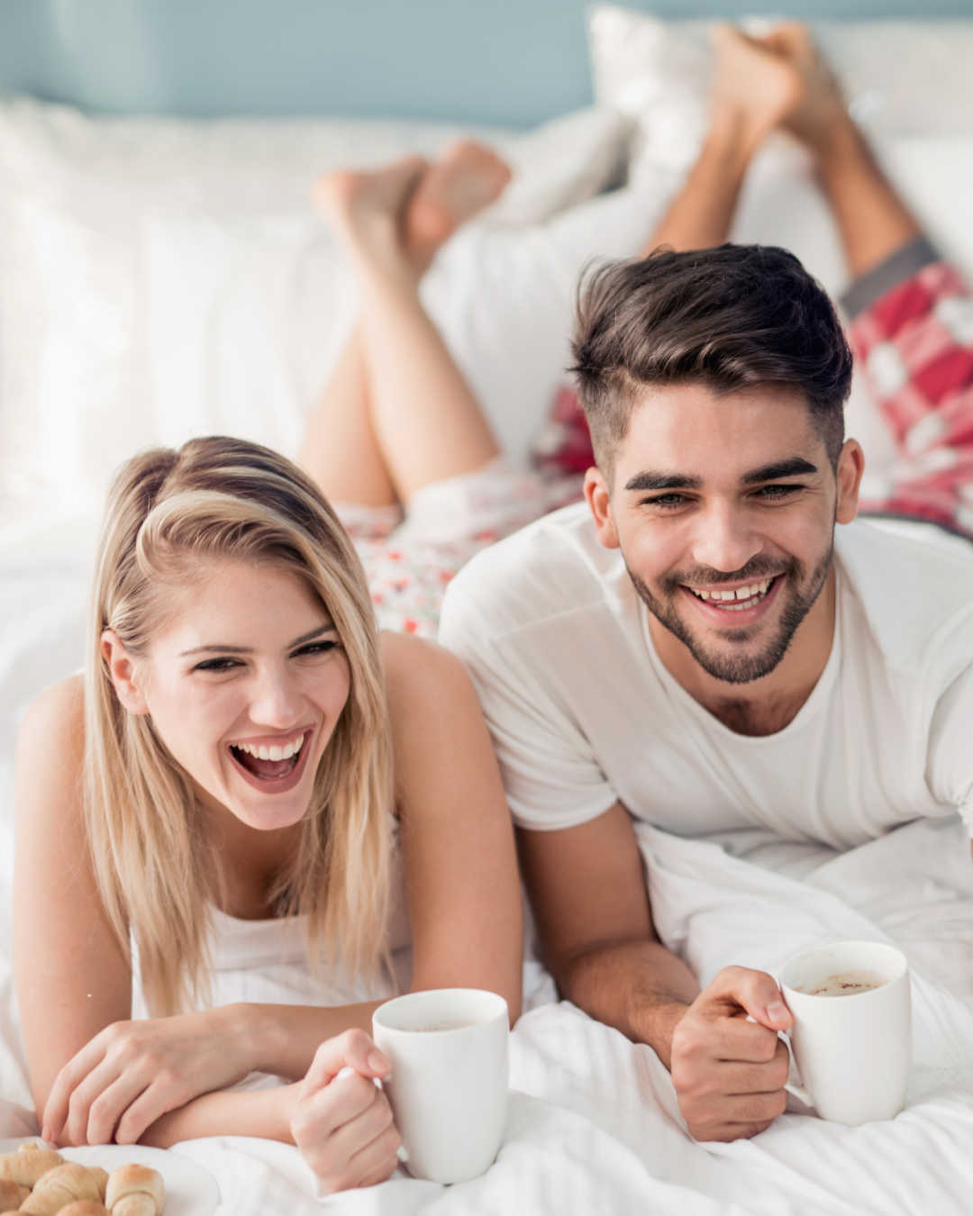 man and woman in bed with coffee