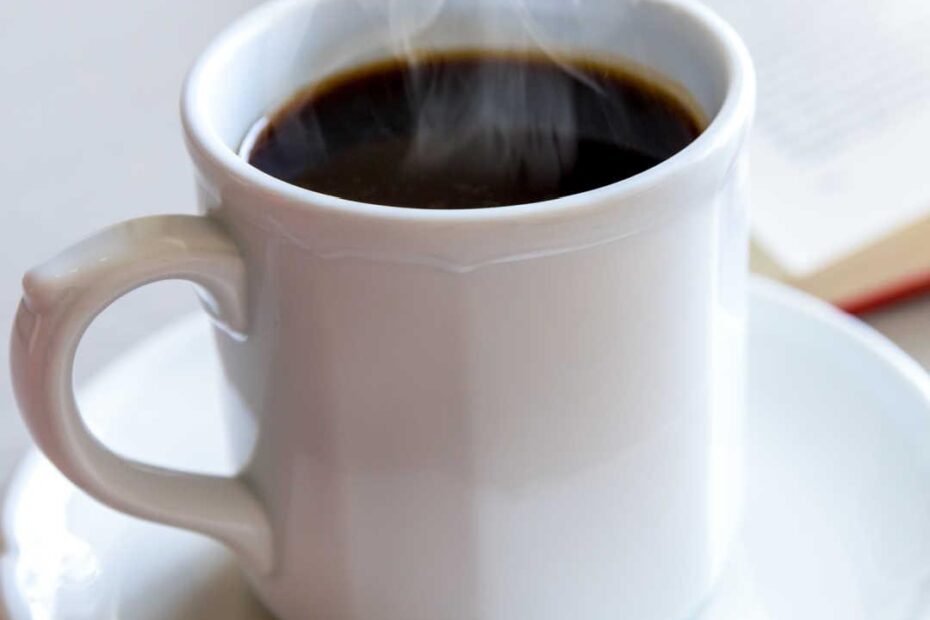 close up of black coffee in mug on table, steam rising