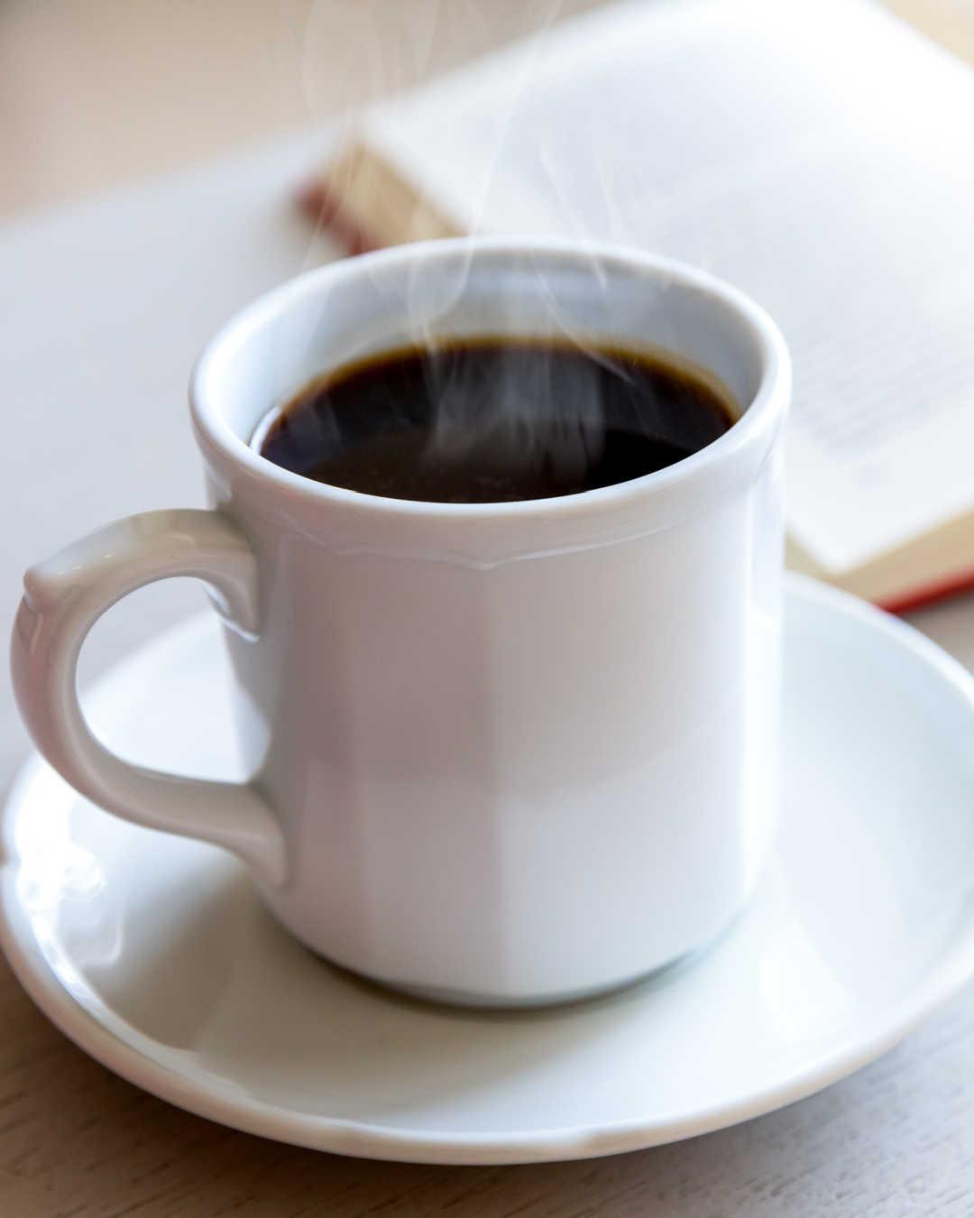 close up of black coffee in mug on table, steam rising
