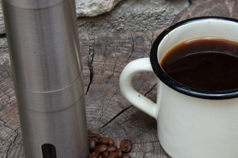 black coffee in mug with beans and grinder