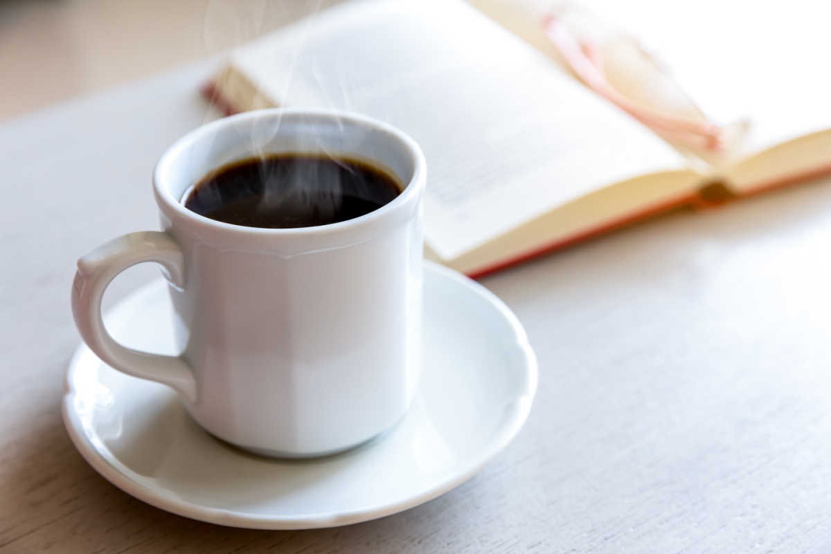 cup of black coffee next to book