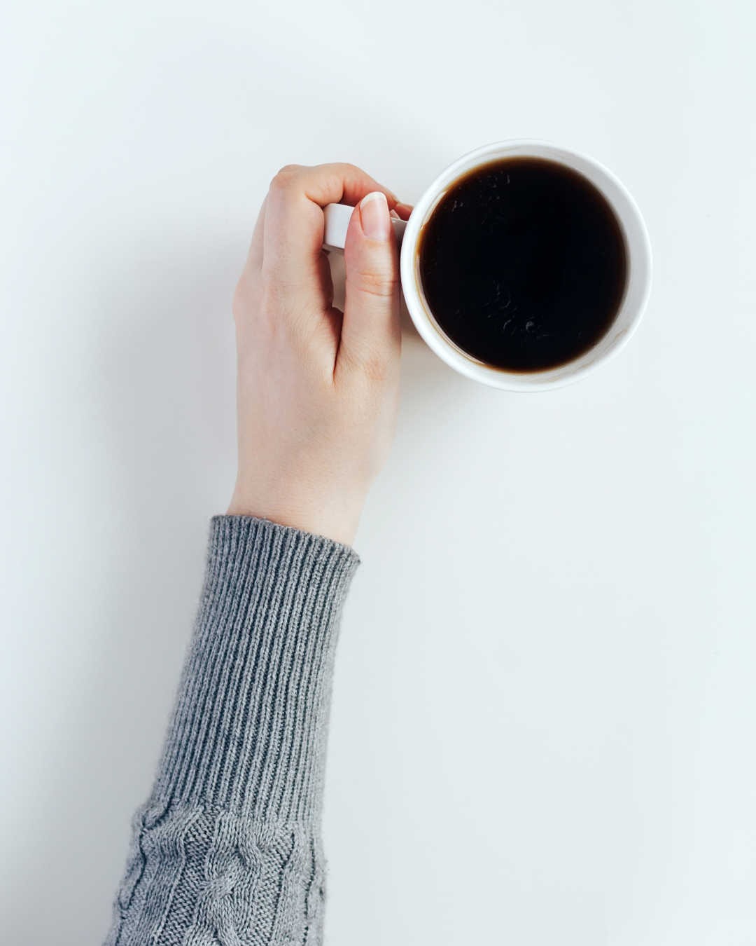 hand holding mug of black coffee