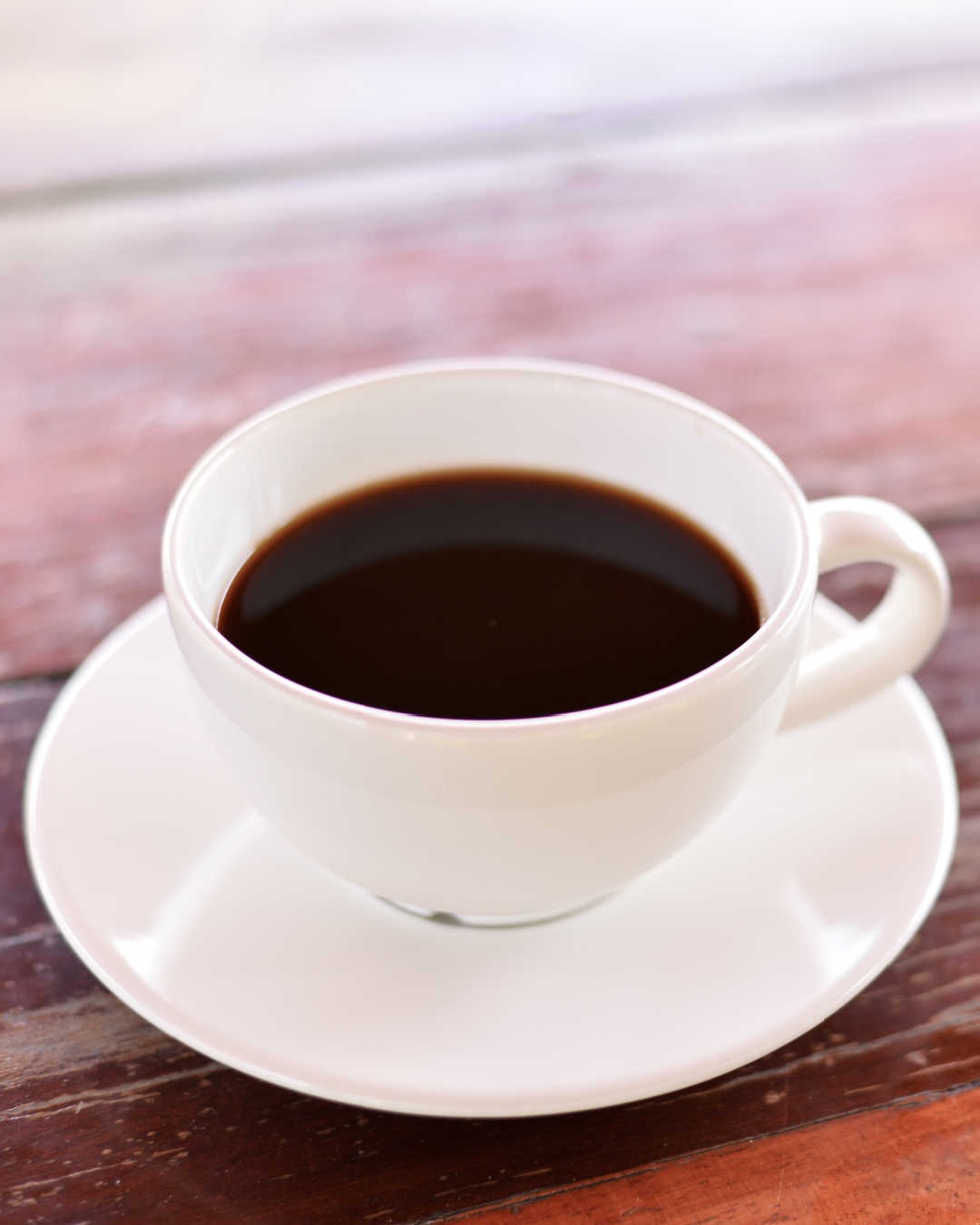 cup of black coffee on simple wood table