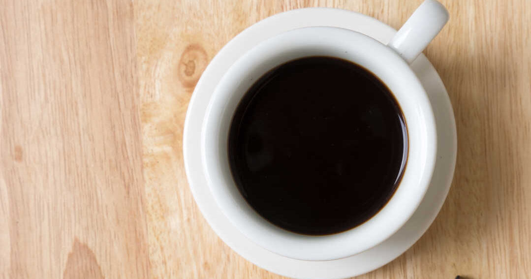 cup of black coffee next to keys